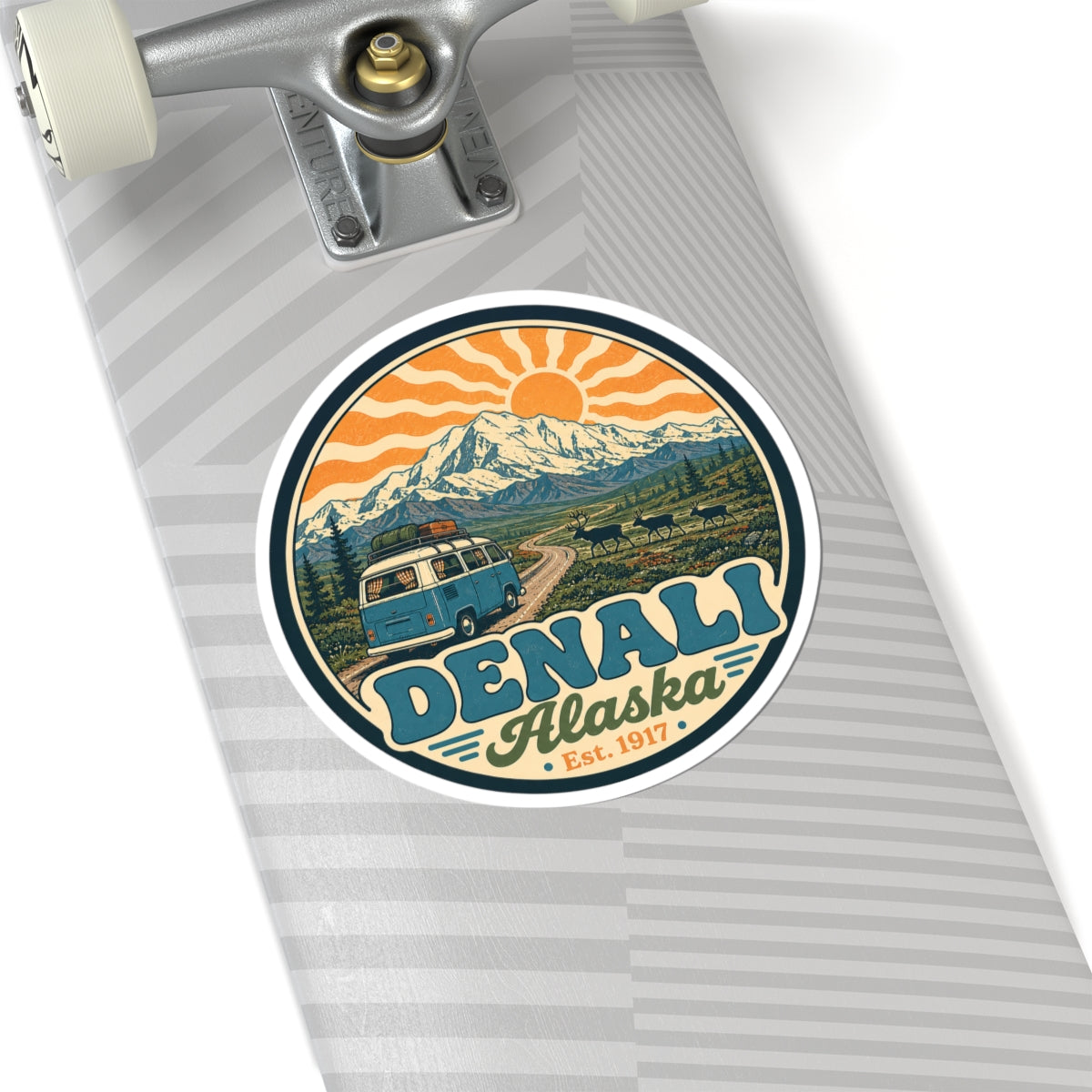 Denali Alaska circular sticker on a notebook, mountain landscape, orange sun rays, teal van