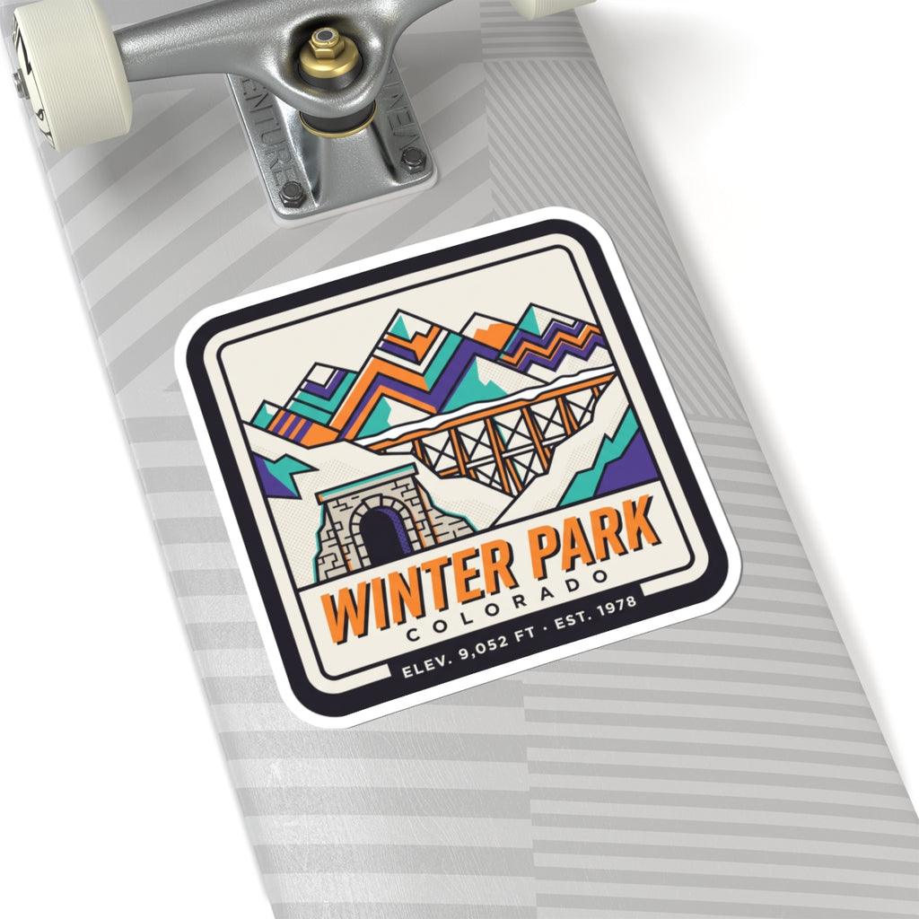 Square retro ski badge sticker on striped fabric, with mountain bridge, tunnel, and Winter Park text