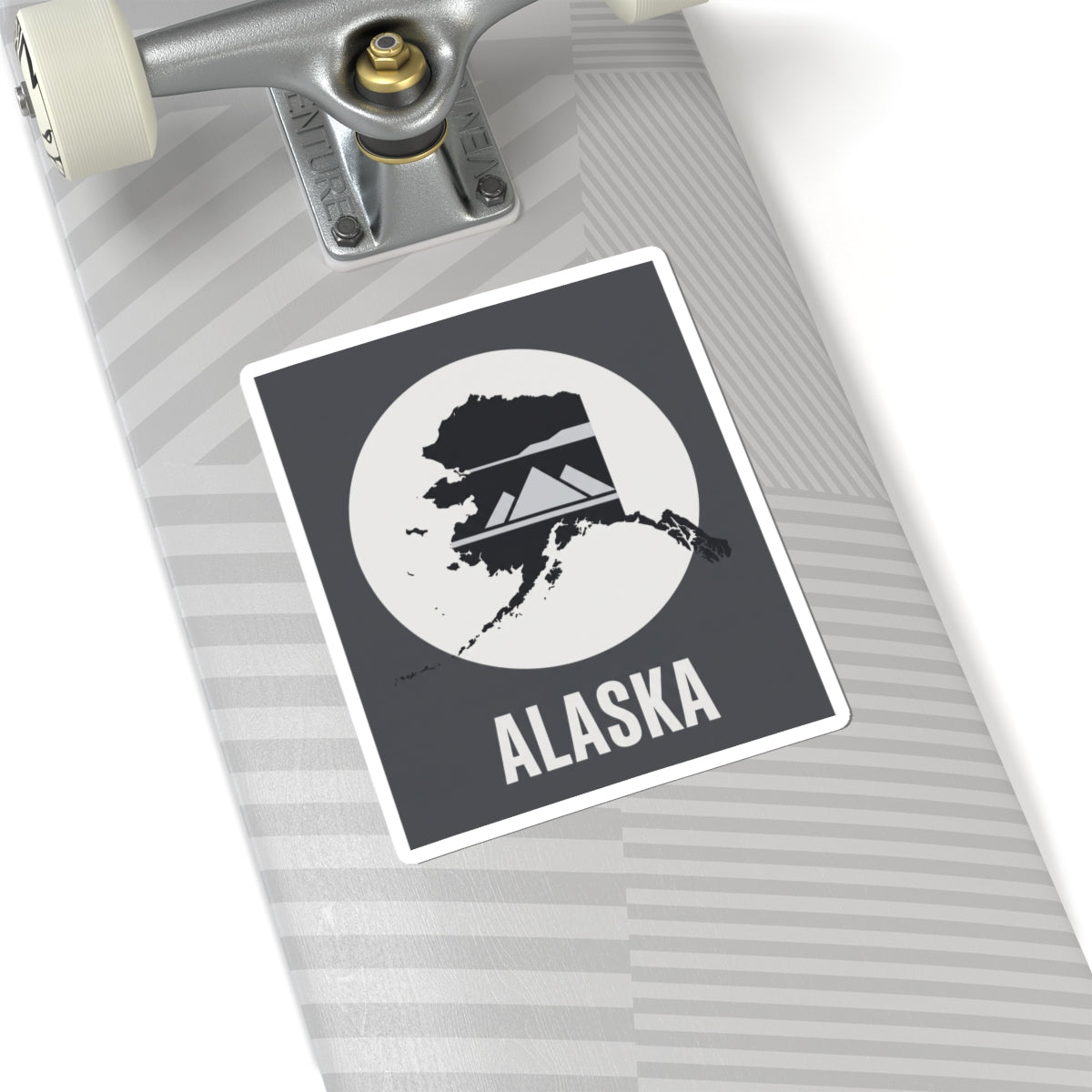 Square Alaska “ALASKA” text vinyl sticker on a notebook, dark gray and white design.