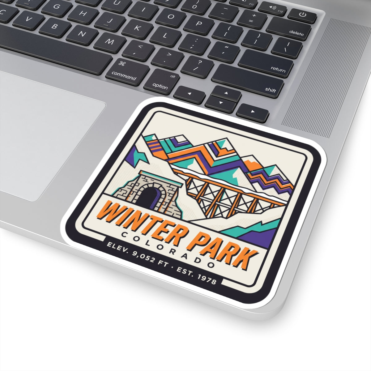 Square retro ski badge sticker on laptop, with mountain bridge, tunnel arch, and Winter Park Colorado