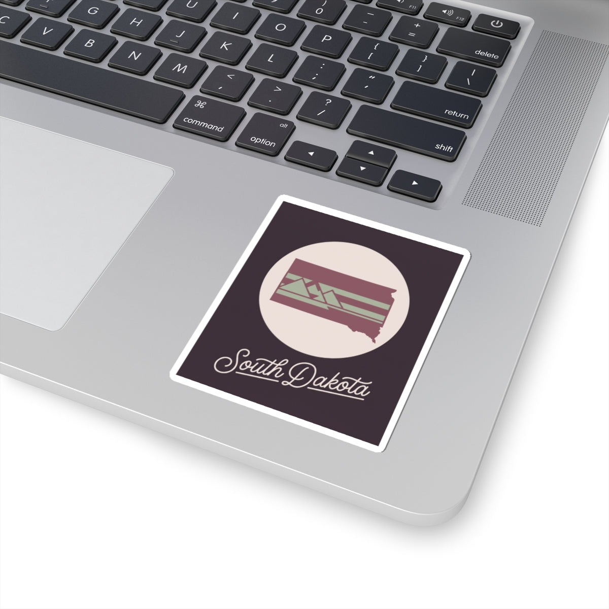 South Dakota kiss-cut decal placed on a laptop, dark purple design with cursive text