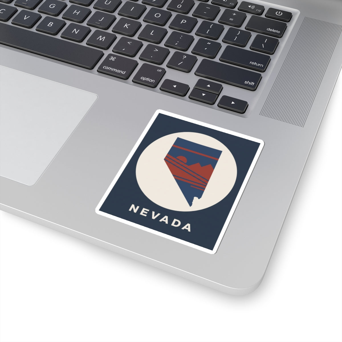Nevada state kiss-cut sticker on a laptop lid, circular emblem with retro mountains