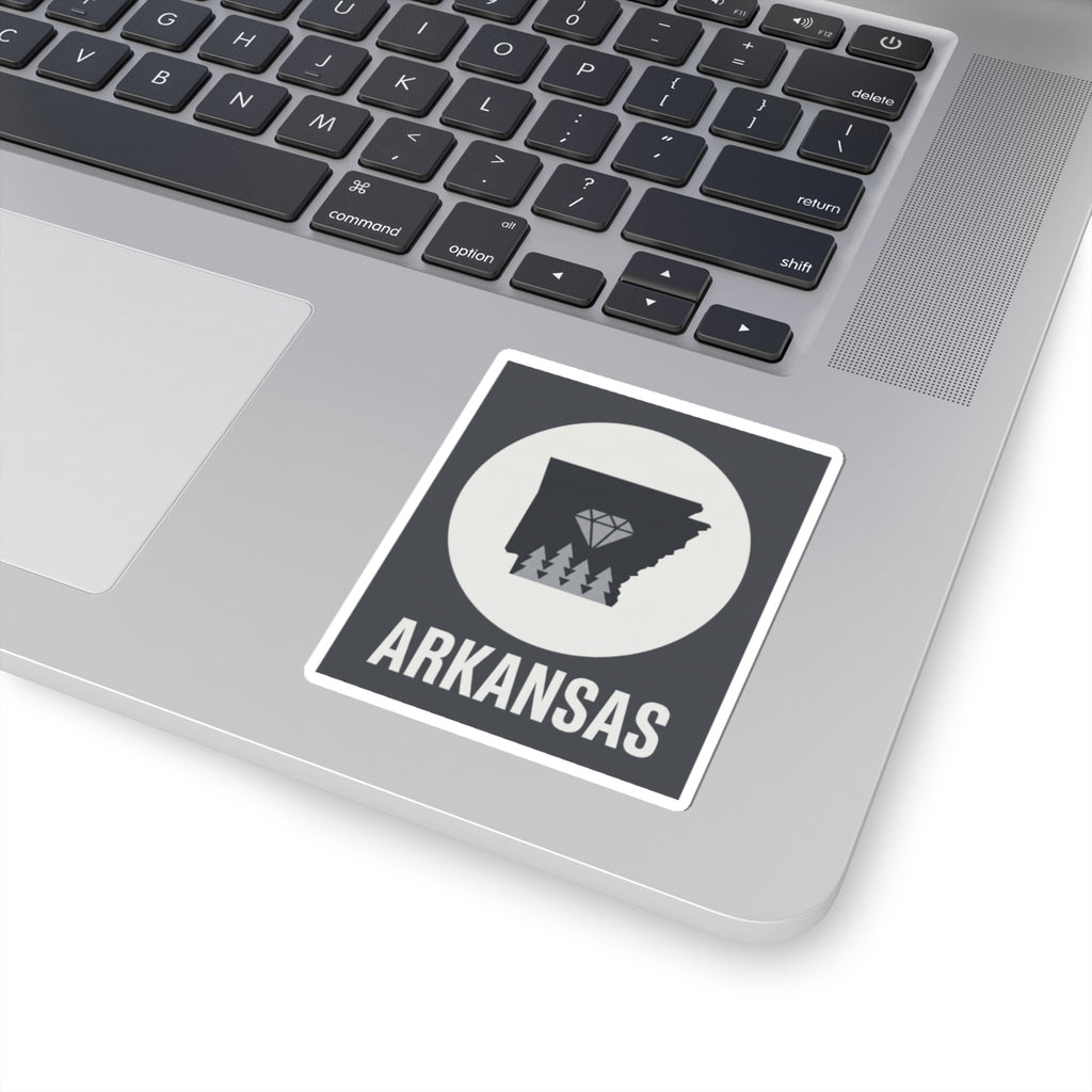 Arkansas vinyl sticker on laptop keyboard: dark state silhouette, diamond trees, ARKANSAS
