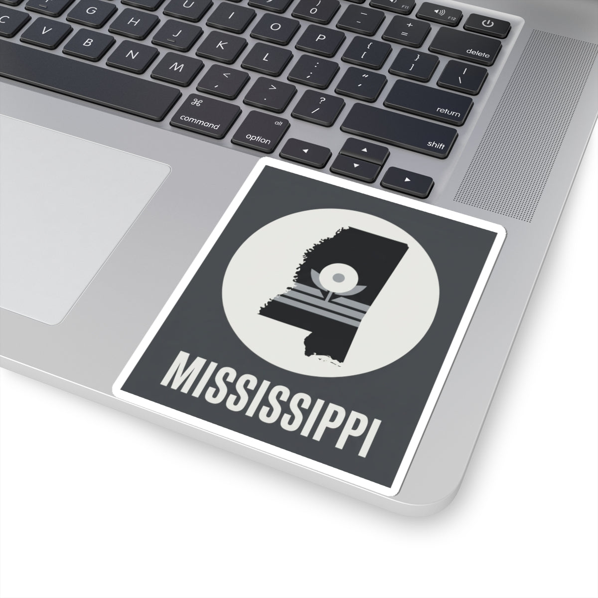 Mississippi silhouette sticker on laptop, bold “MISSISSIPPI” under circular emblem