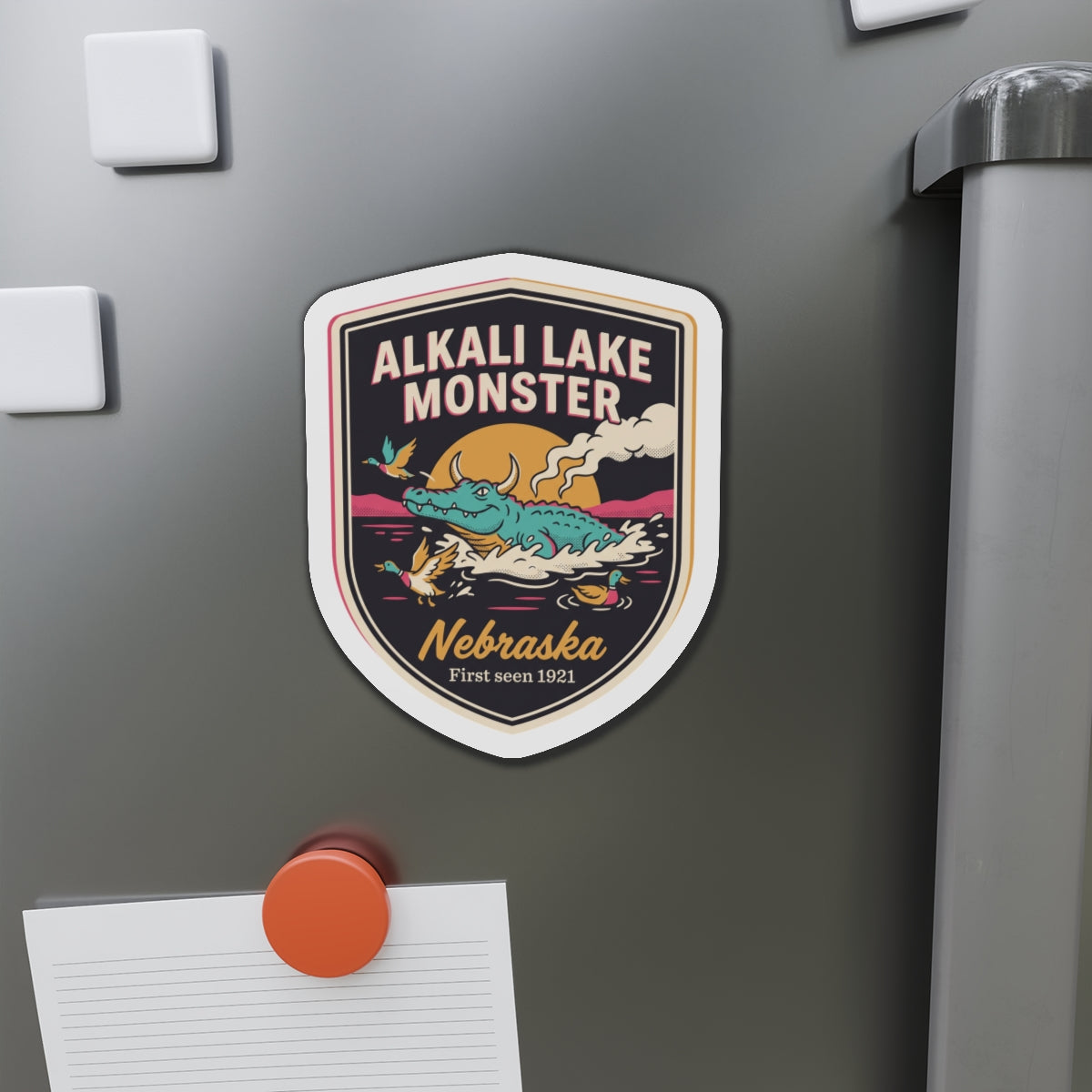 Shield die-cut magnet featuring Alkali Lake Monster with canoe and Nebraska badge