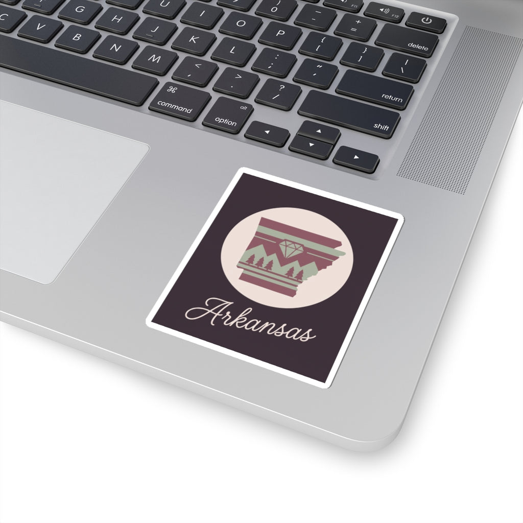 Arkansas state silhouette vinyl sticker on laptop keyboard, maroon and green circular emblem