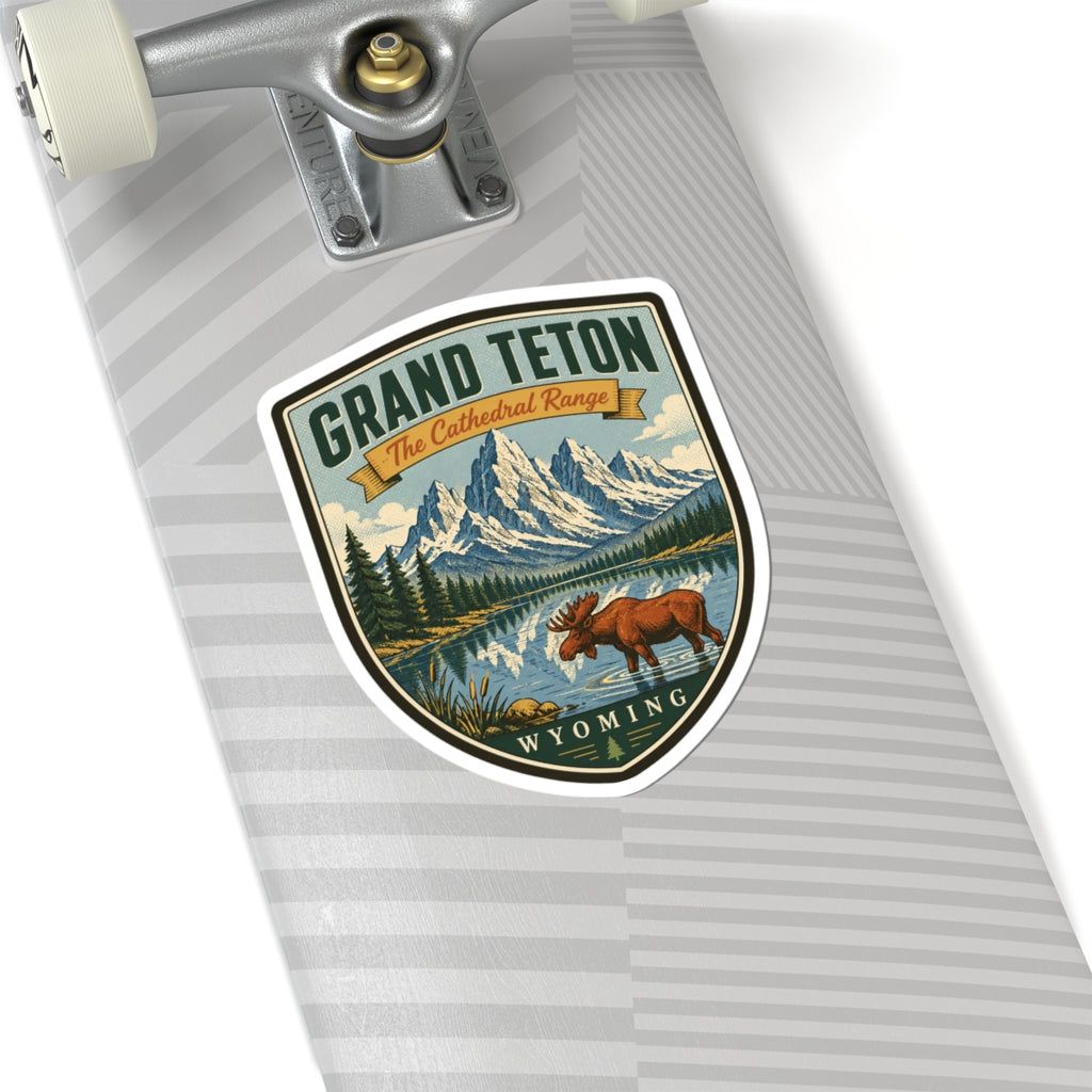 Shield-shaped travel sticker on skateboard deck, showing moose, mountain peaks, lake, and Wyoming text.