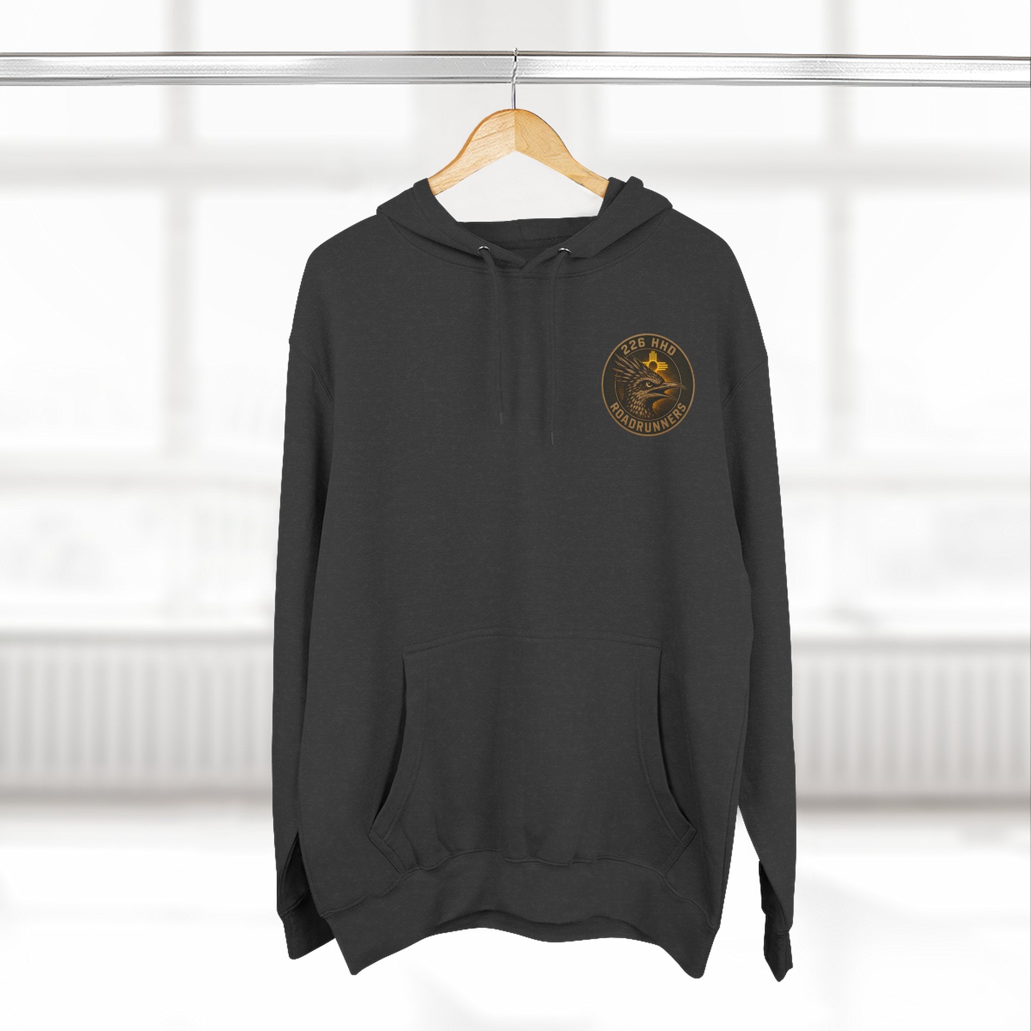 Black pullover hoodie hanging on a hanger with hood and front kangaroo pocket