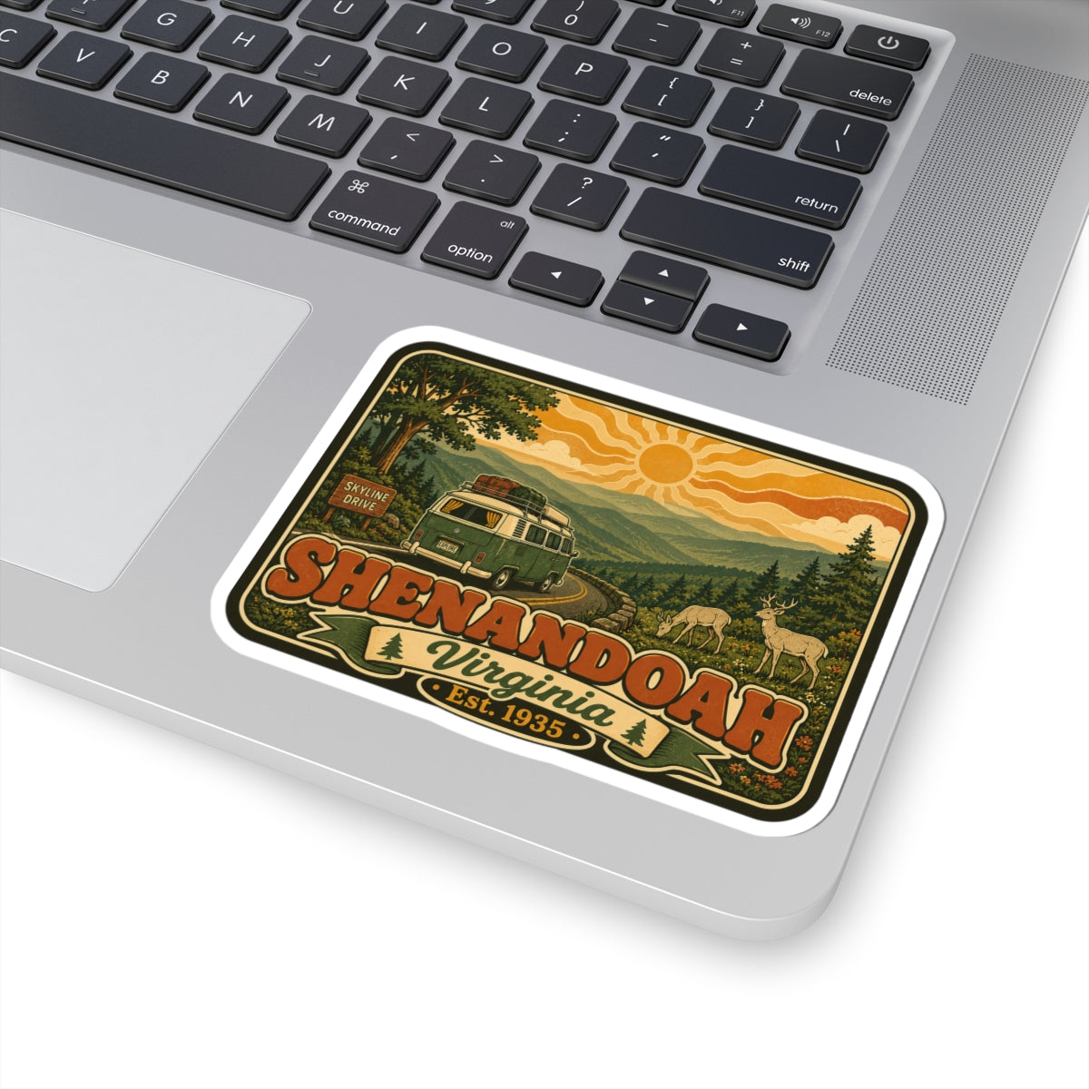 Kiss-cut sticker on laptop: rounded white border with green camper, deer, and "Est. 1935"