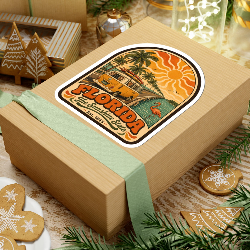 Florida sticker on wrapped gift box, featuring retro surf bus, palm trees, sun, and flamingo