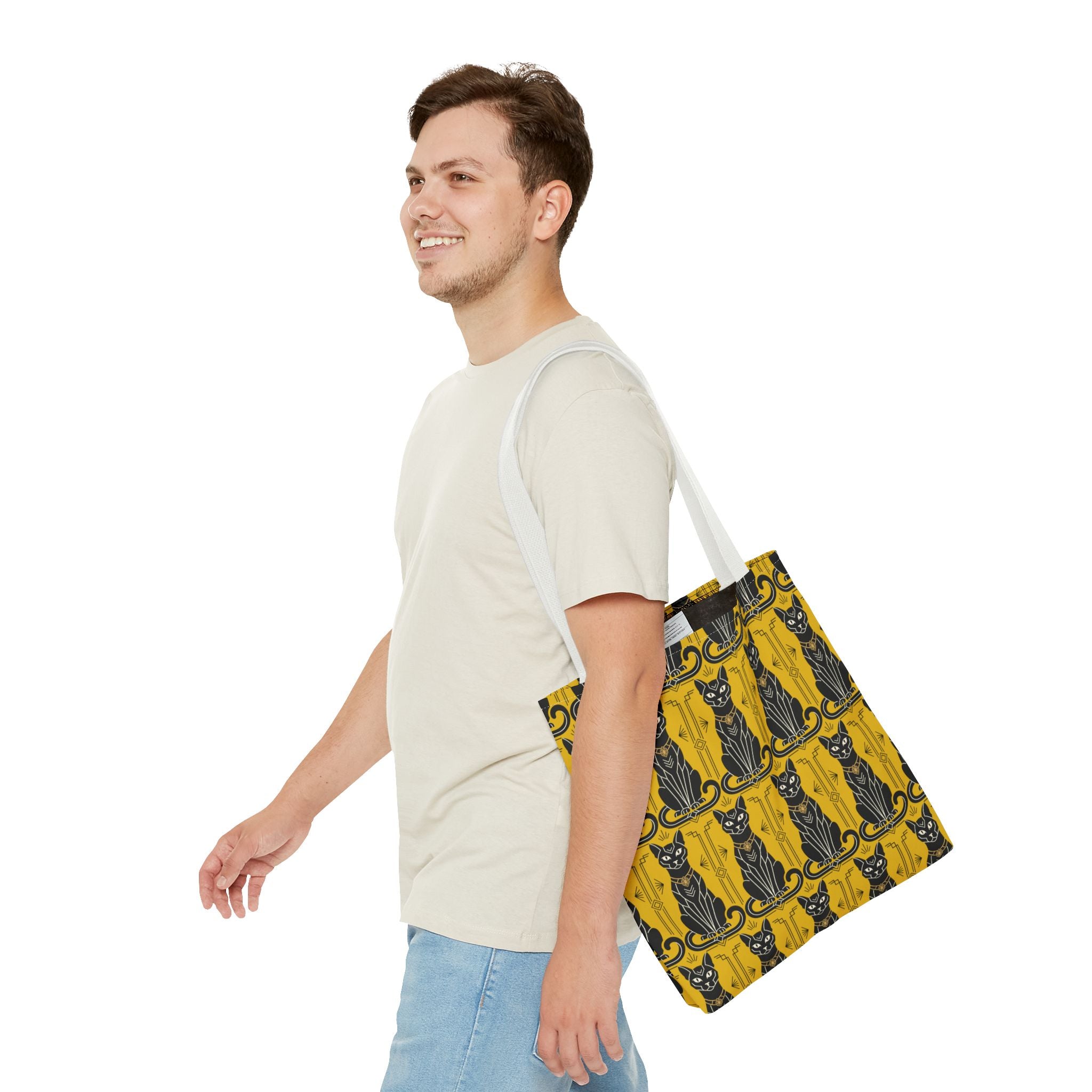 Yellow cat-pattern tote bag with black cats and navy swirls, white handles over shoulder.