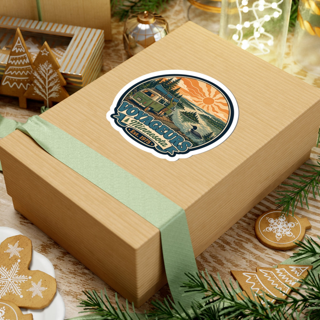 Round die-cut sticker with vintage scene: green camper van, lake, pine trees, orange sun; Est. 1975
