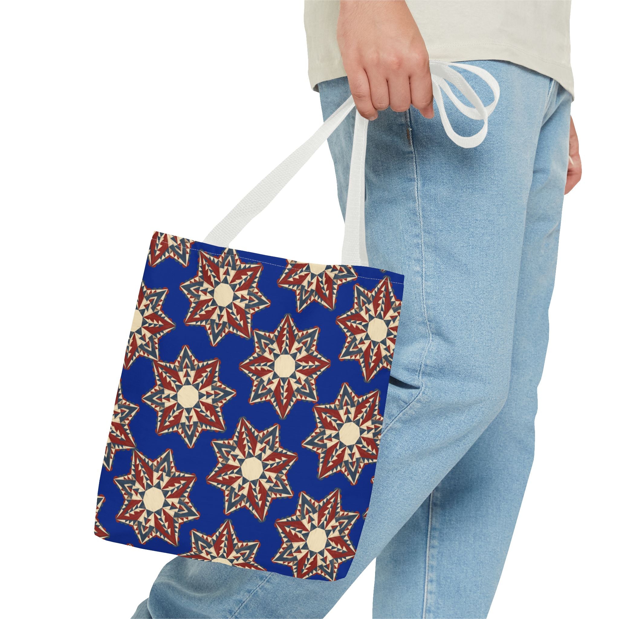 Blue starburst floral tote bag with white handles held by a person in jeans