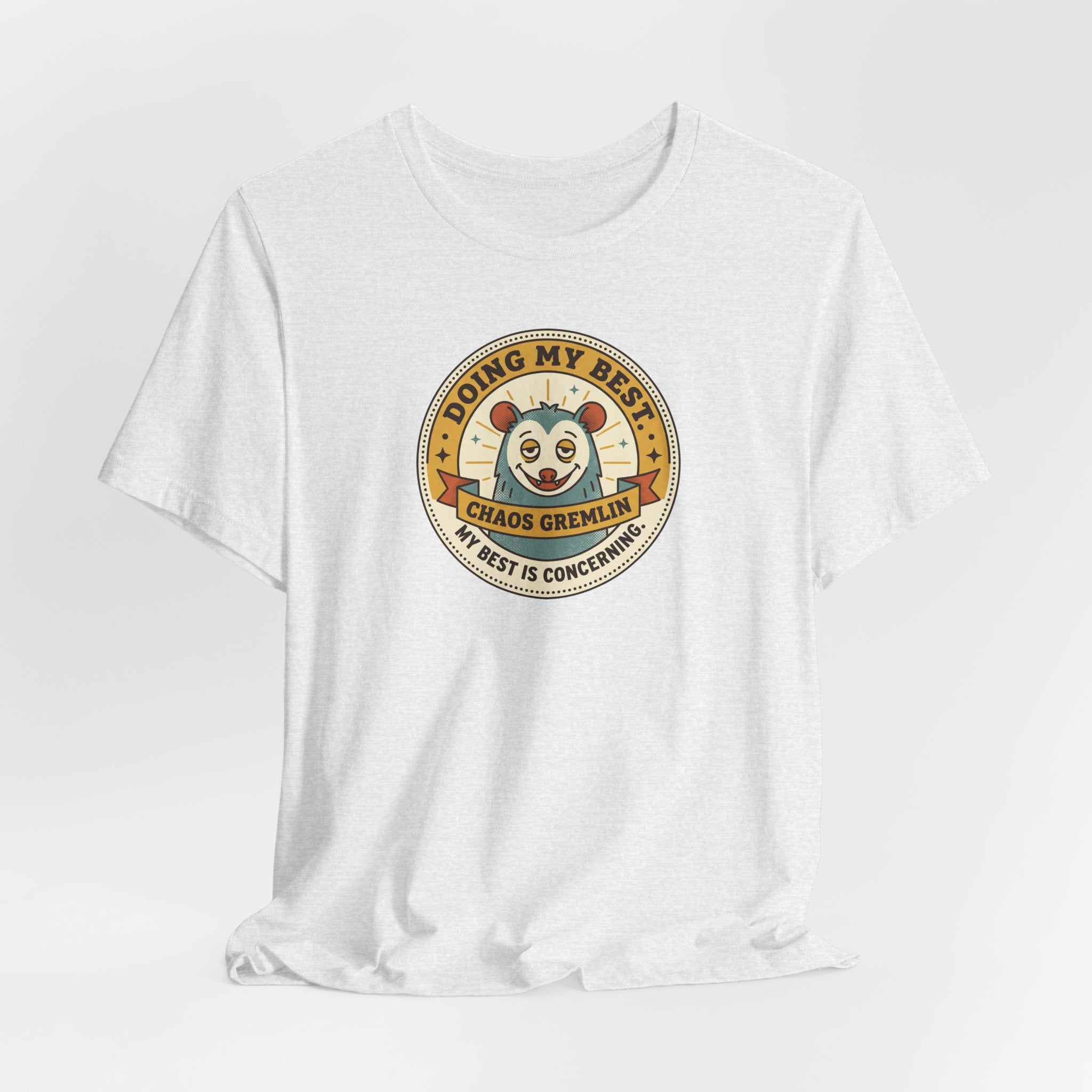 Light grey T-shirt with round cartoon gremlin badge graphic centered on the chest