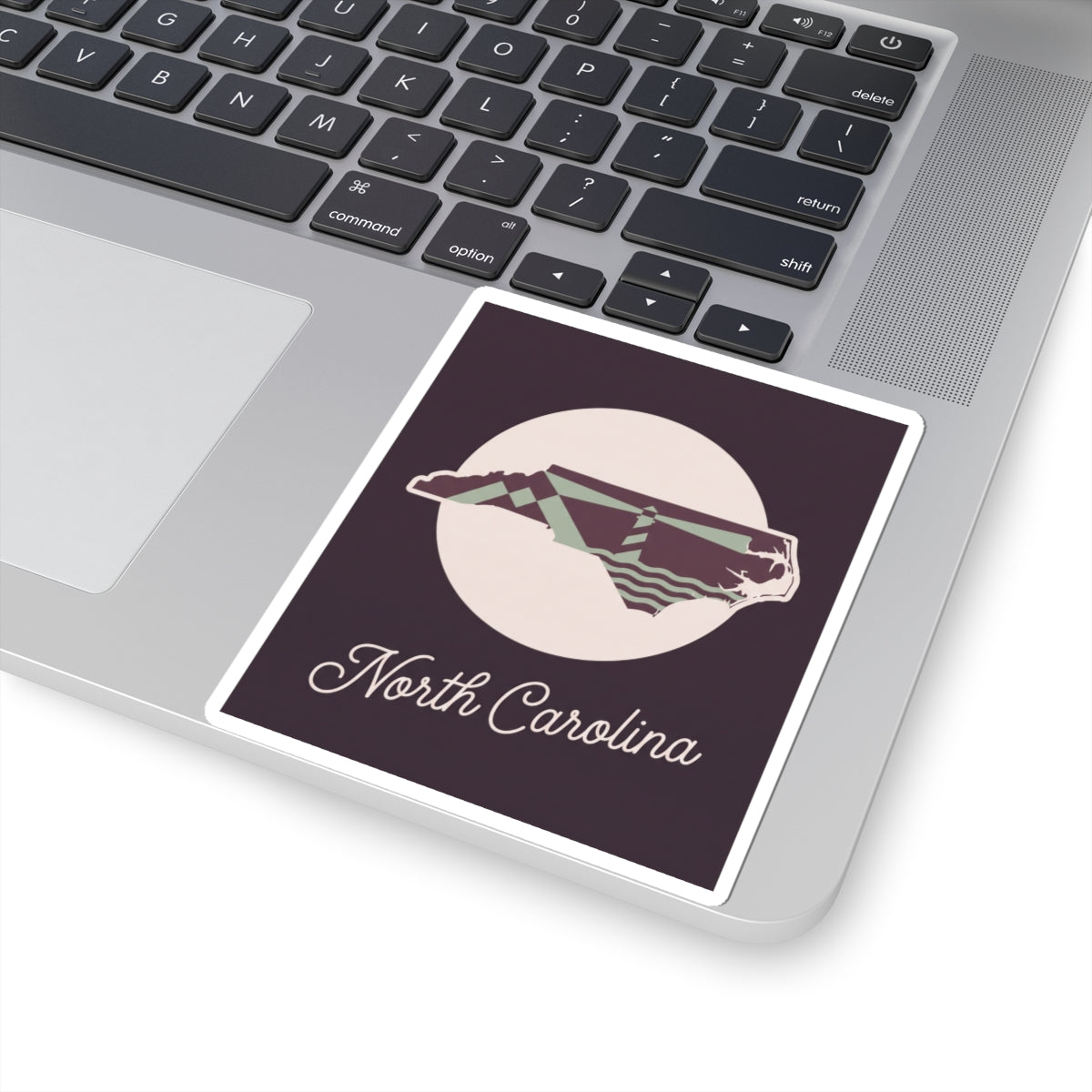 North Carolina decal sticker on laptop keyboard, purple panel with state outline and “North Carolina”