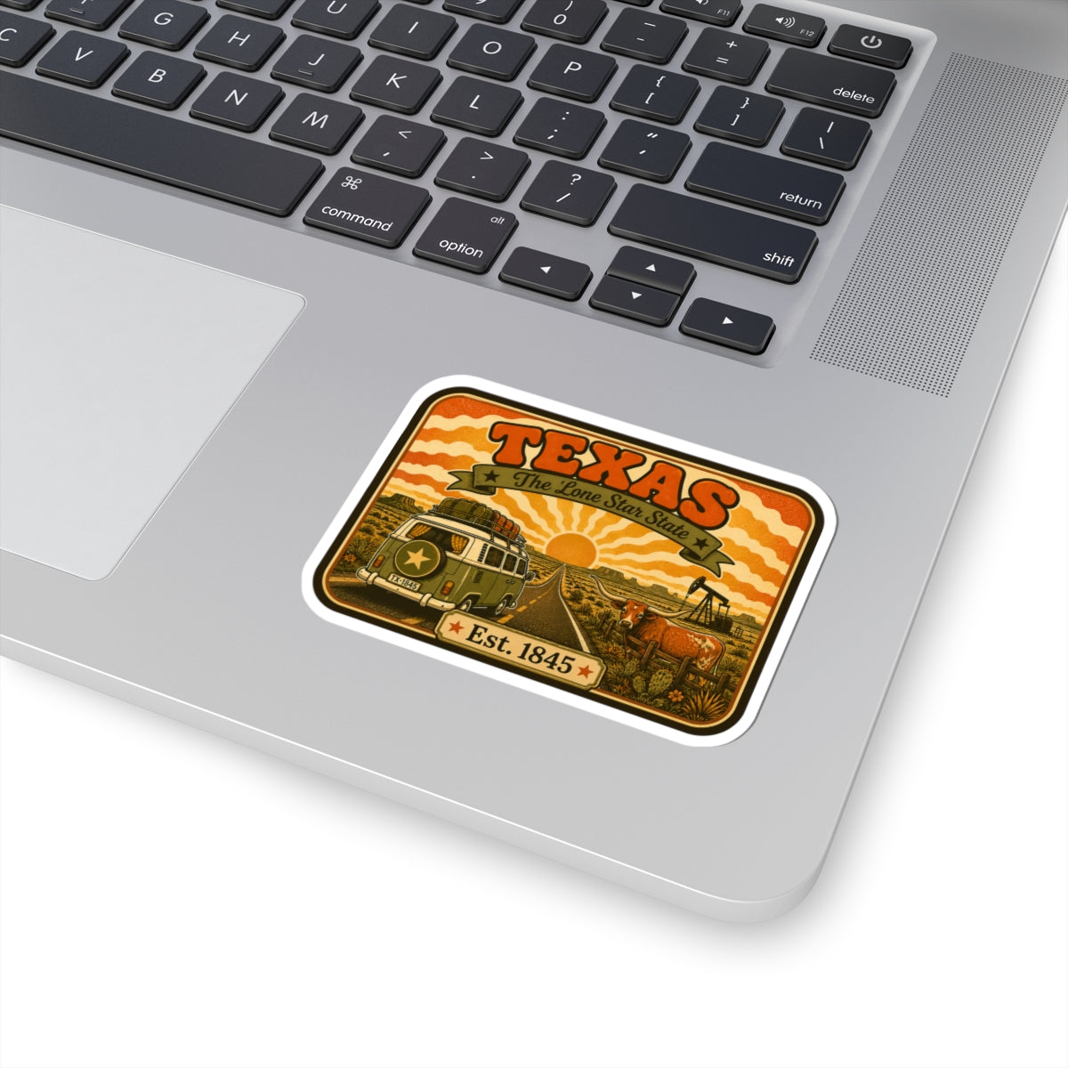 Kiss-cut Texas road trip sticker on silver laptop trackpad