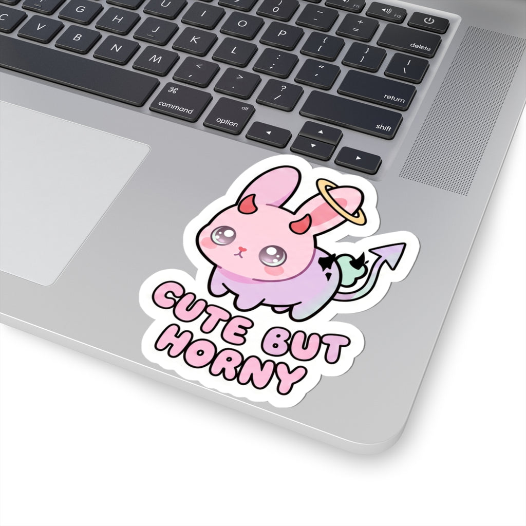 Cute demon bunny kiss-cut sticker on laptop lid with halo ring and 'Cute But Horny' lettering