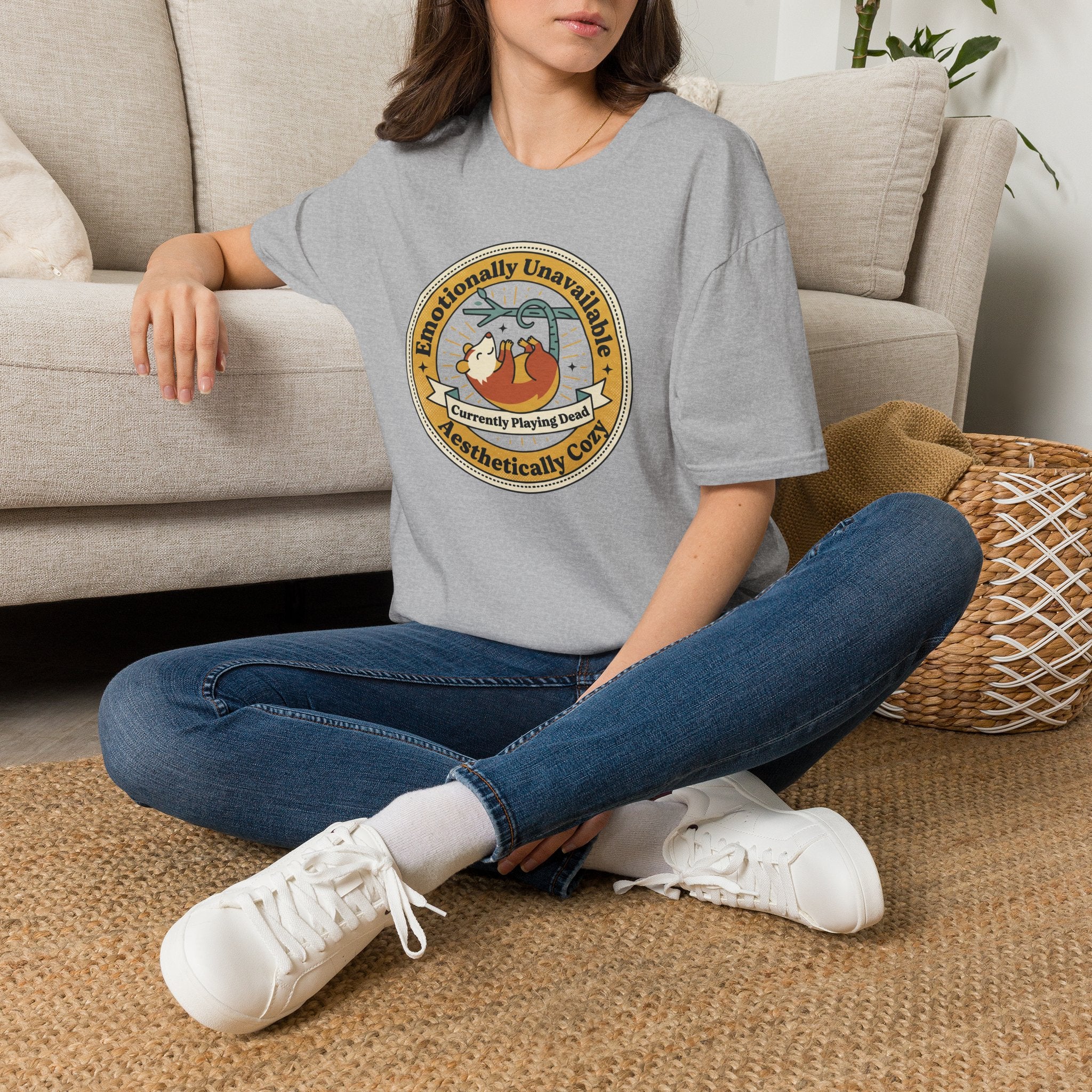 Light gray T-shirt with round sloth graphic front, worn by model sitting with jeans