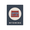 Wyoming state metal art sign, dark blue square with oval mountains logo and “WYOMING” text.