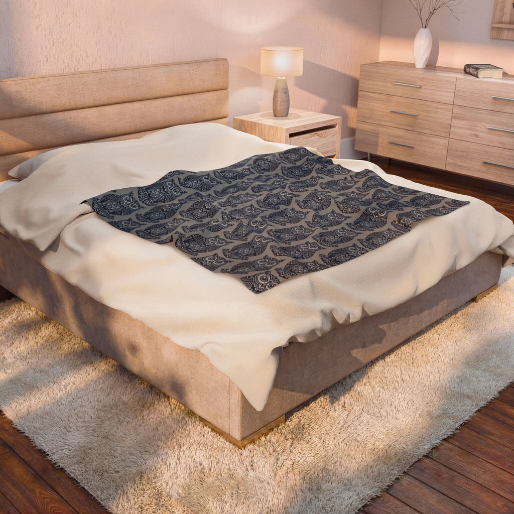 Velveteen plush blanket with repeating blue owl pattern on dark navy base