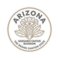 Circular Arizona state flower sticker with saguaro cactus blossom and text, beige on clear.