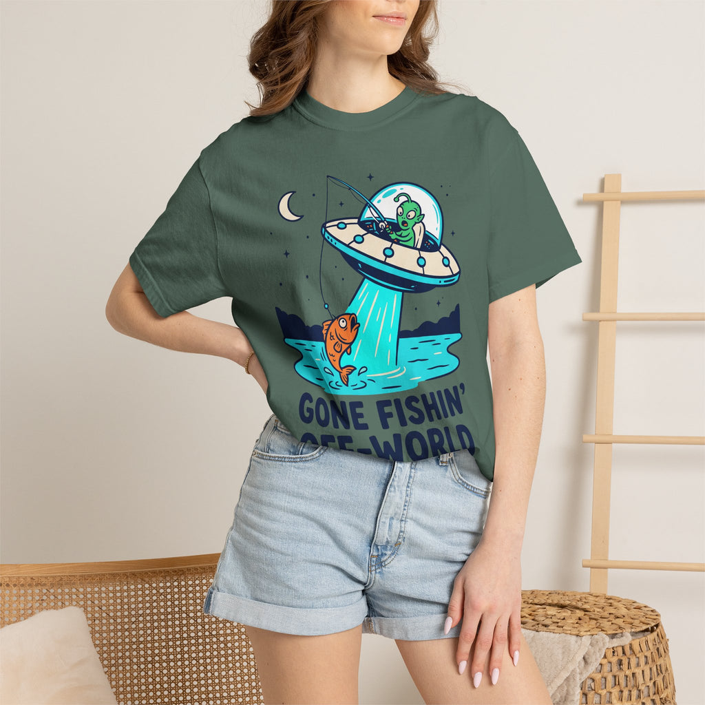 Dark green graphic T-shirt on model featuring UFO fishing scene with alien and fish.