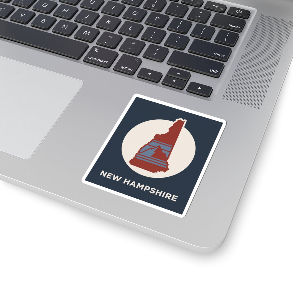 New Hampshire state silhouette sticker on a laptop: navy design with red state map and white circle