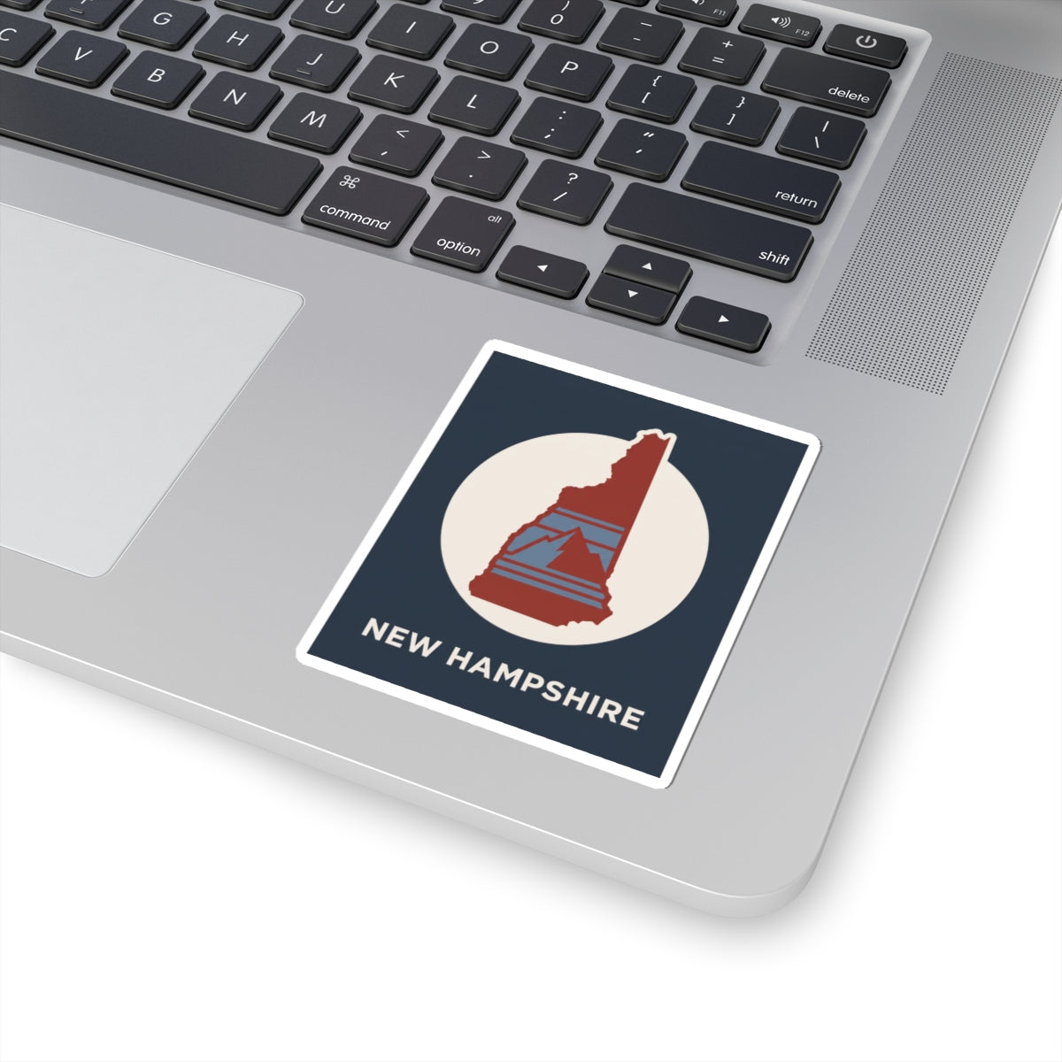 New Hampshire state silhouette sticker on a laptop: navy design with red state map and white circle