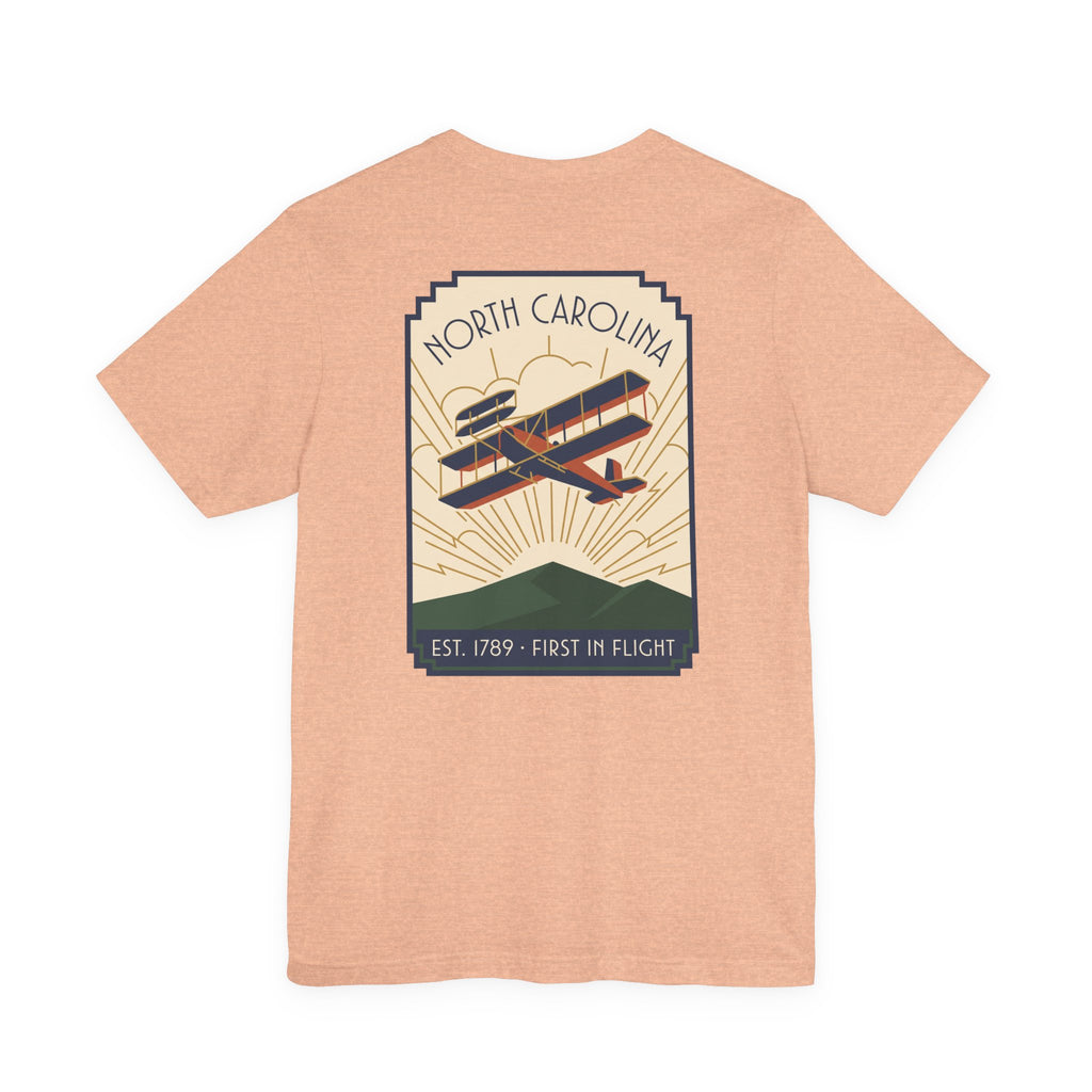 Light peach t-shirt with North Carolina biplane graphic and 'Est. 1789 - First in Flight' text
