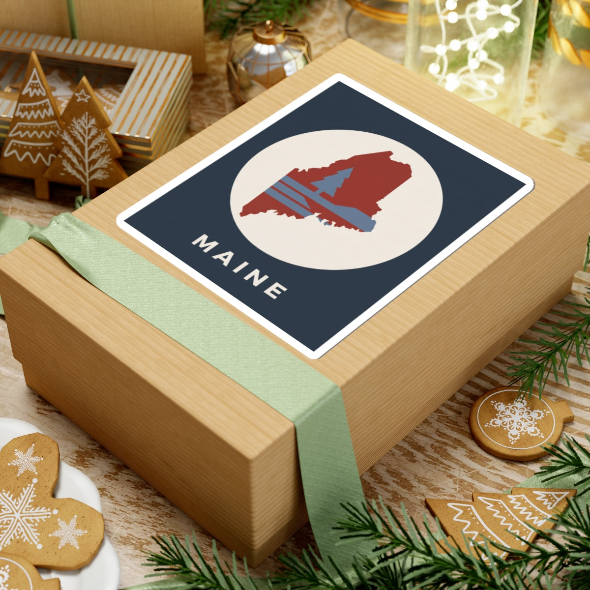 Maine state silhouette sticker on gift box top: navy square with red map graphic and “MAINE”