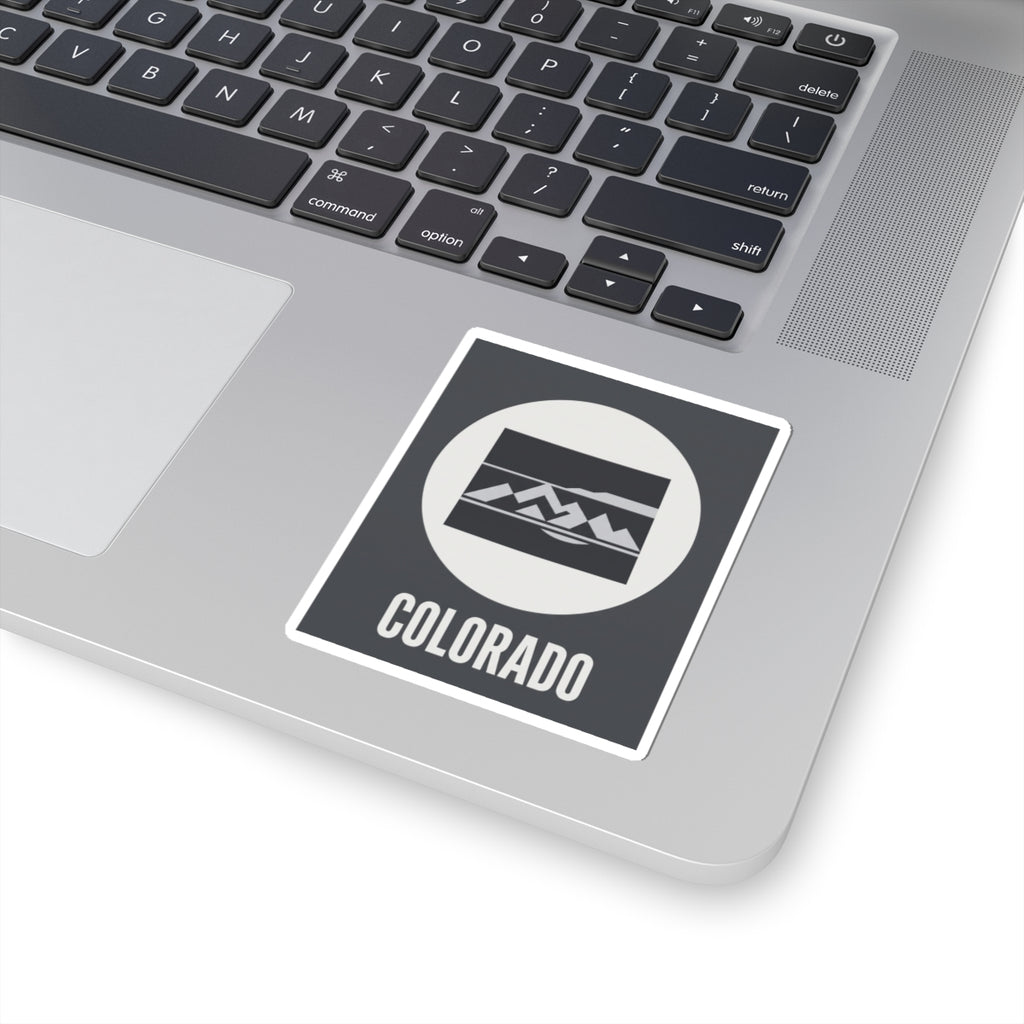 Colorado badge sticker placed on a dark square with white border, mountain emblem, and COLORADO