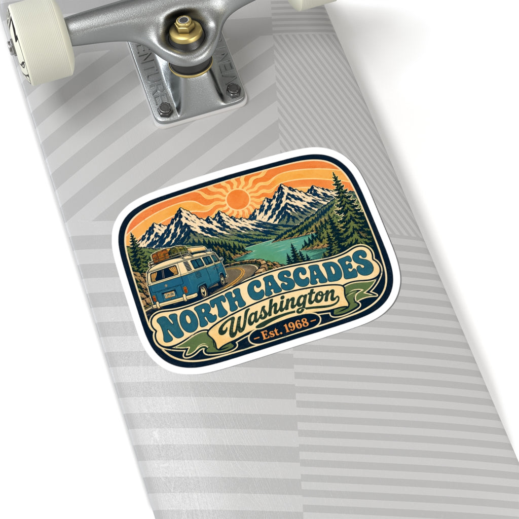 North Cascades sticker on a skateboard deck, with camper van and mountain peaks