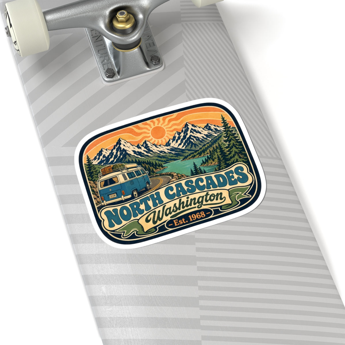 North Cascades sticker on a skateboard deck, with camper van and mountain peaks