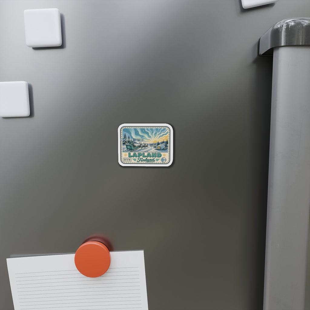 Die-cut Lapland travel sticker magnet attached to a metal fridge door, aurora scene and text