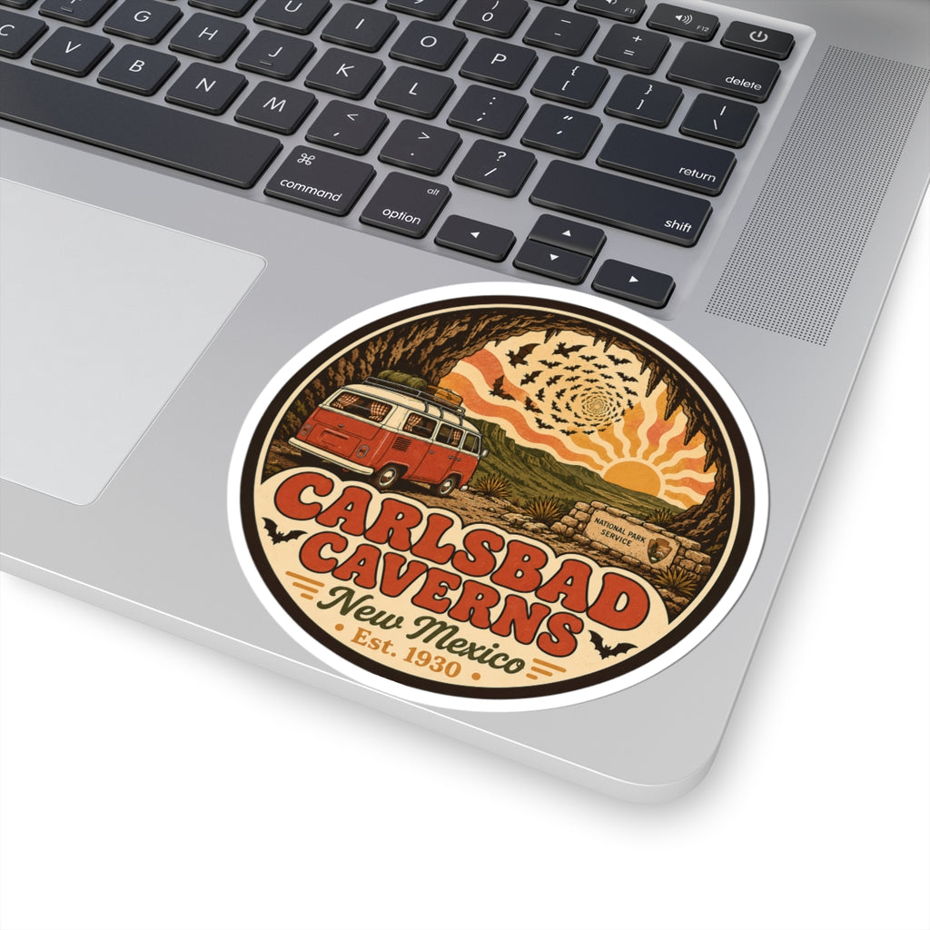 Round Carlsbad Caverns sticker on laptop trackpad area, showing orange camper van and cave artwork