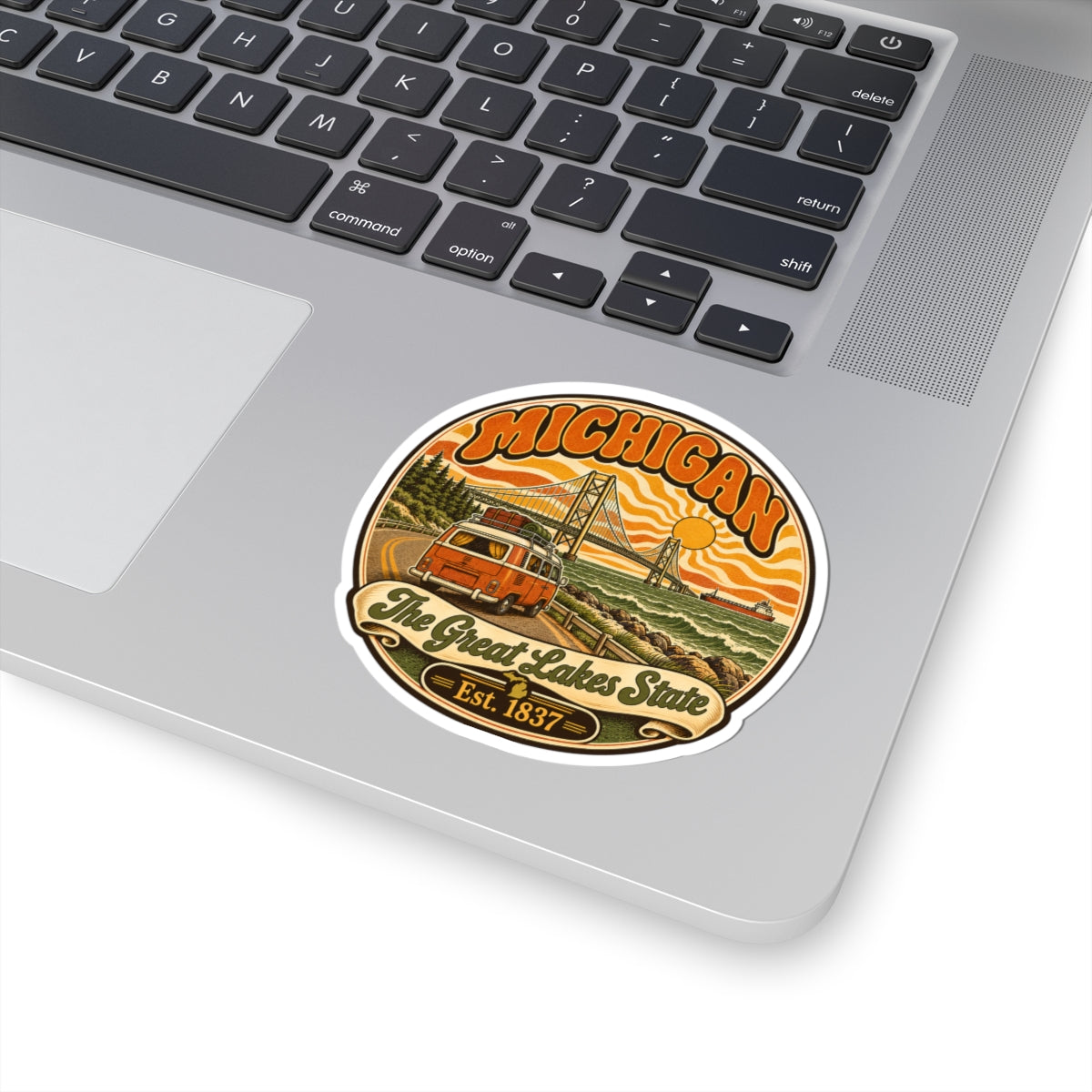 Michigan sticker with orange camper, suspension bridge, lake waves, “The Great Lakes State,” Est. 1837