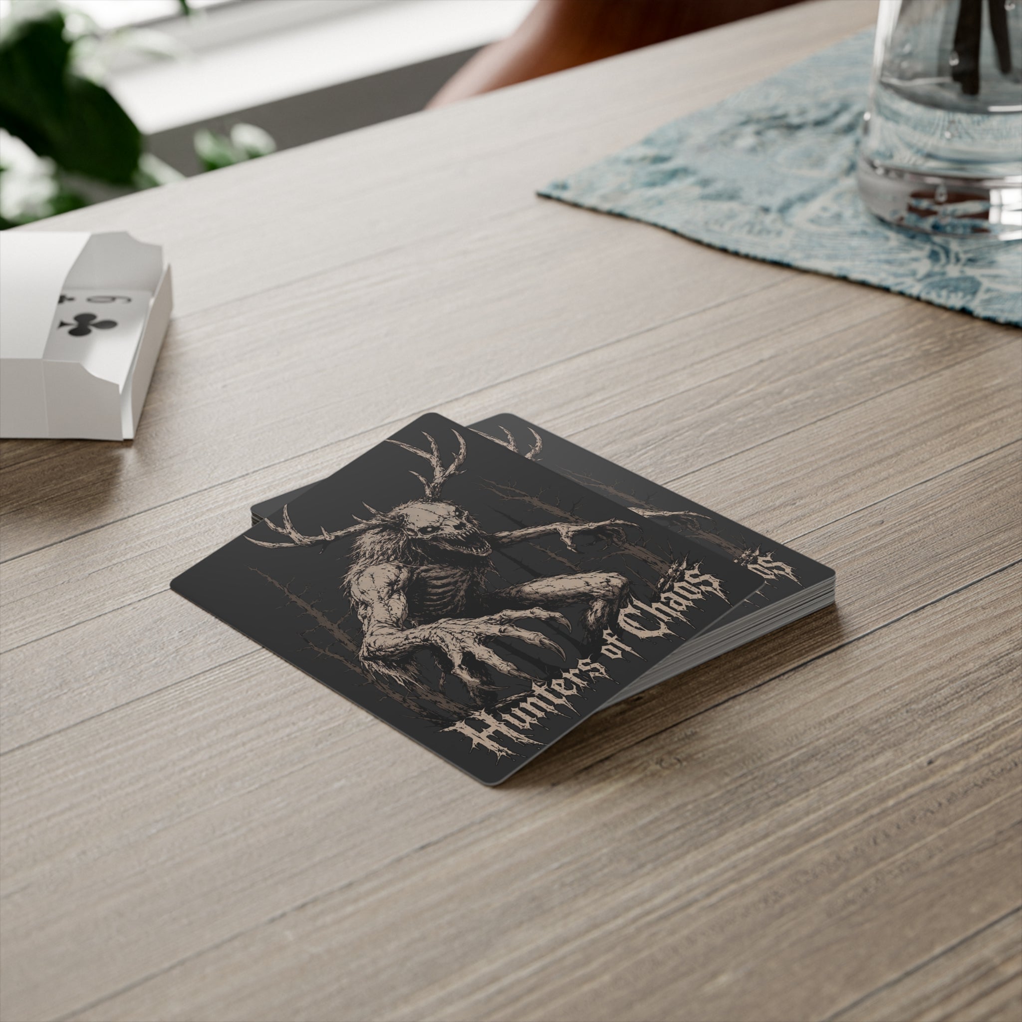 Hunters of Chaos poker card with antlered skull design near a deck box