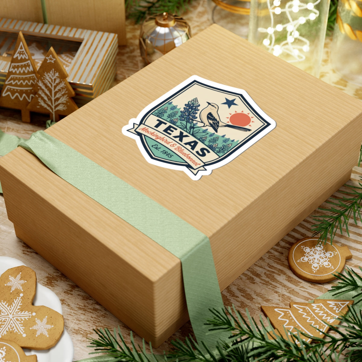 Texas badge sticker on wrapped gift, mockingbird and bluebonnet artwork with TEXAS and Est. 1845