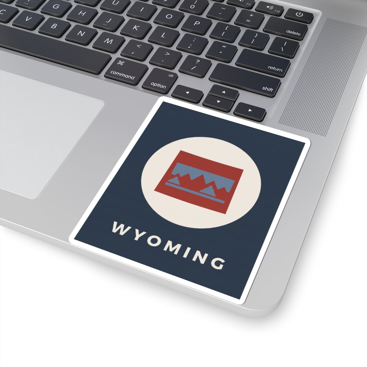 Square Wyoming sticker with circular mountains badge, red/blue lines, and “WYOMING” text.