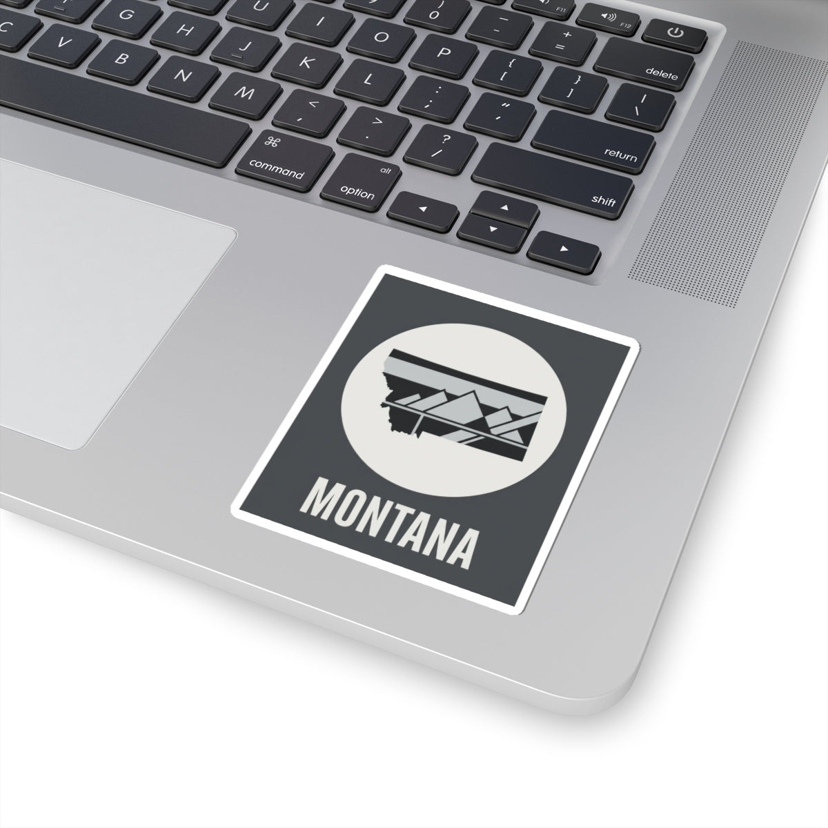 Montana mountain badge sticker on laptop, white circle emblem with landscape graphic and MONTANA text