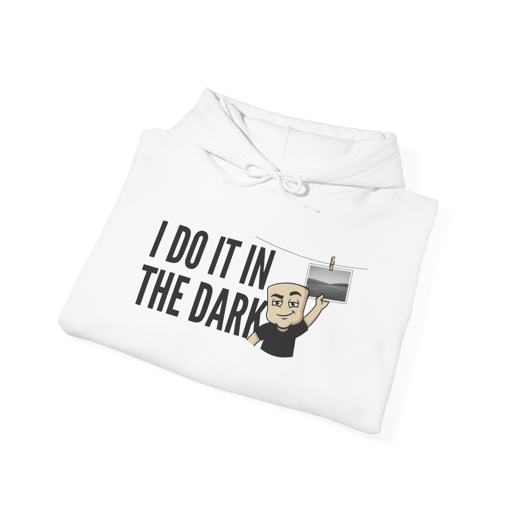 White hoodie folded with “I DO IT IN THE DARK” graphic and small cross icon