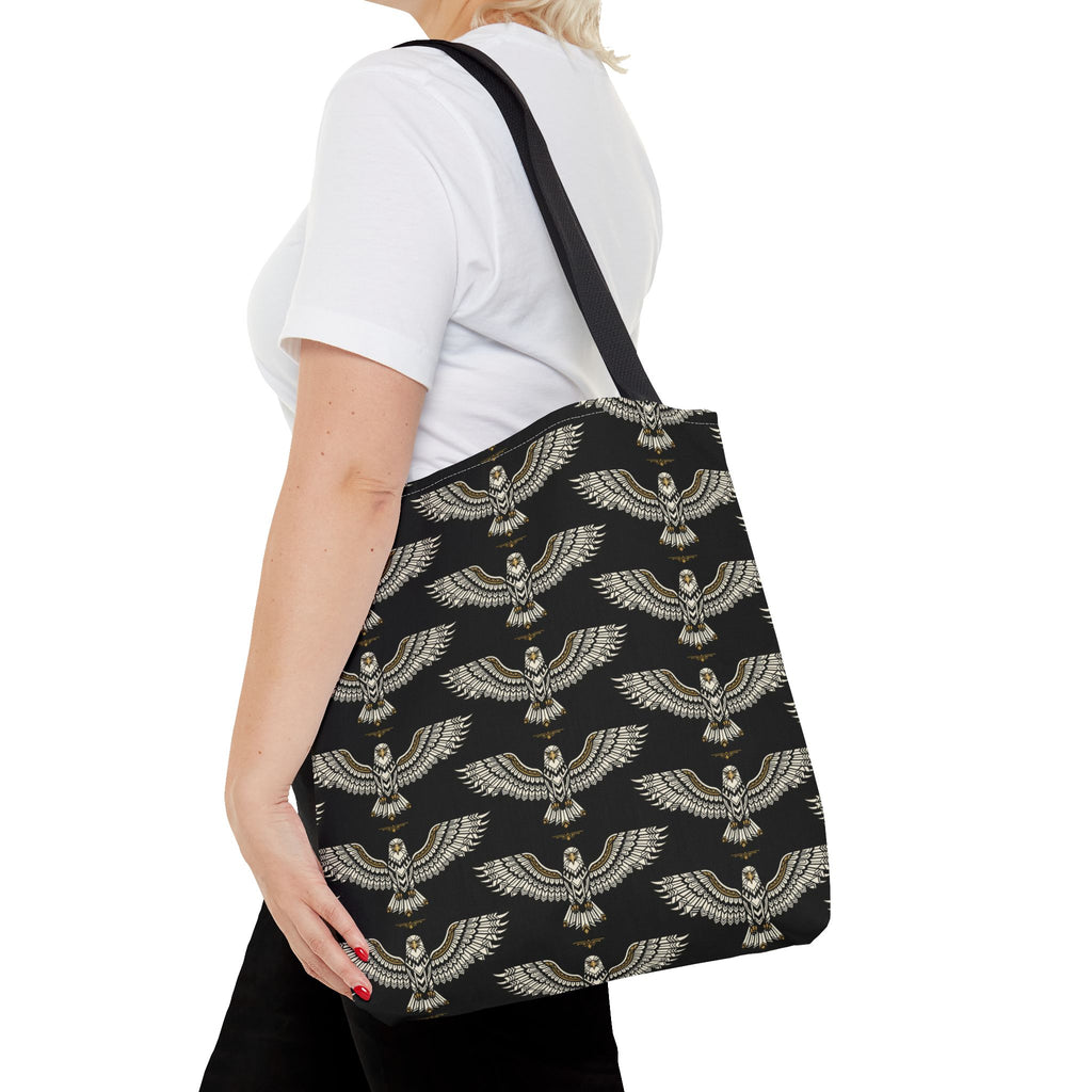 Black tote bag with gold winged scarab pattern, side view worn on shoulder