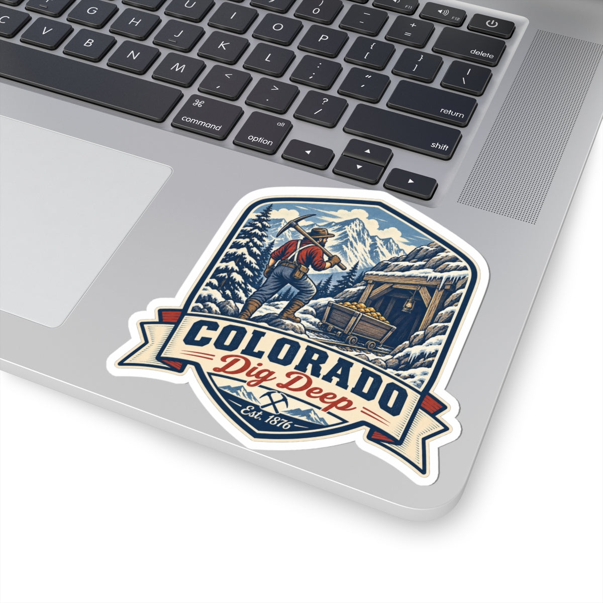 Die-cut sticker with Colorado banner and miner digging scene, snowy mountains, Est. 1876