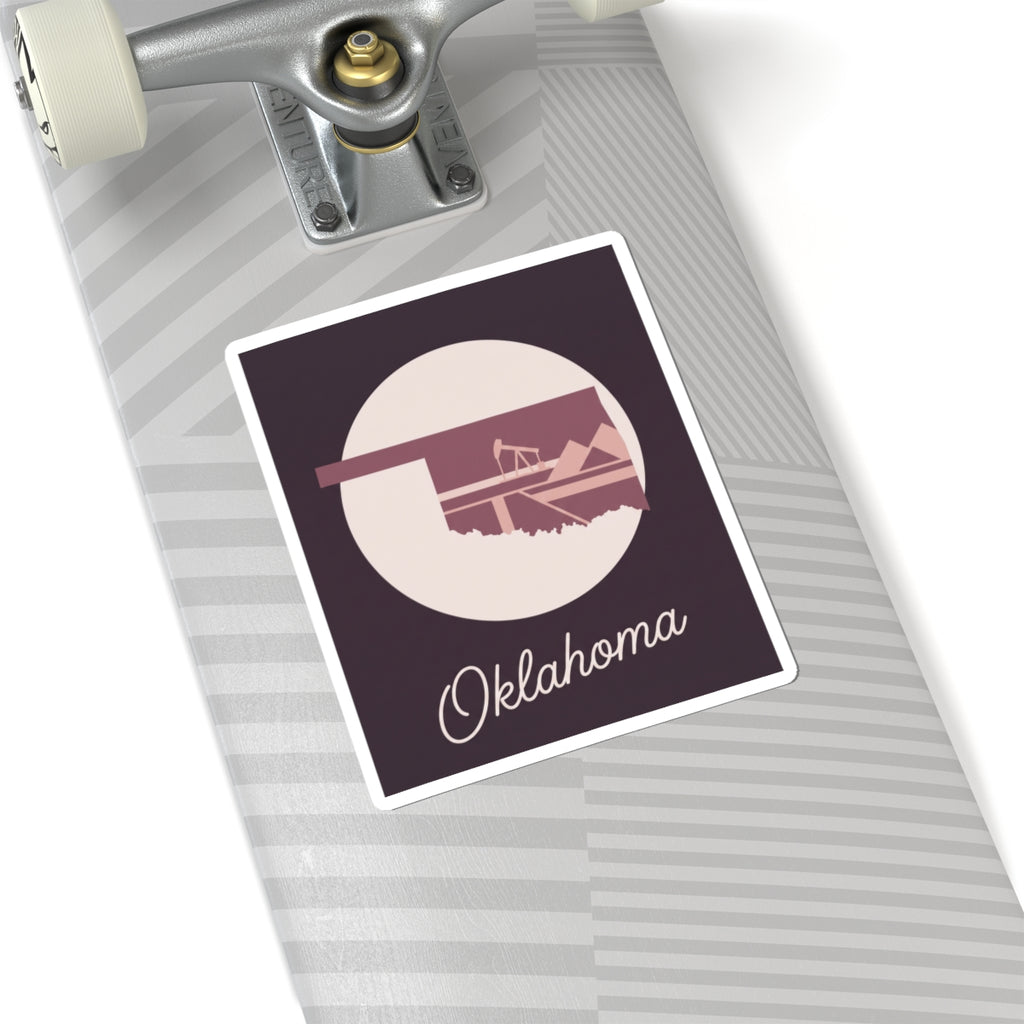 Oklahoma state sticker on striped luggage: maroon square with oil derrick silhouette and Oklahoma