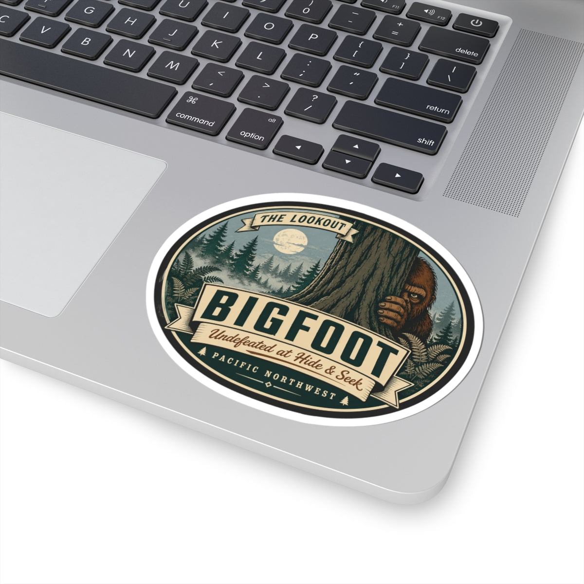 Round kiss-cut Bigfoot outdoor logo vinyl sticker centered on laptop keyboard