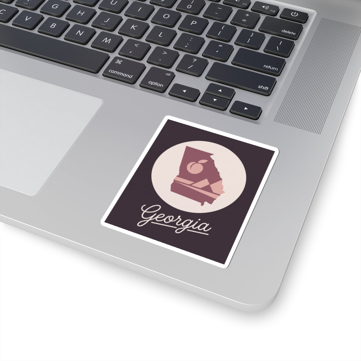 Mauve Georgia state silhouette vinyl decal on a laptop lid with cursive Georgia script