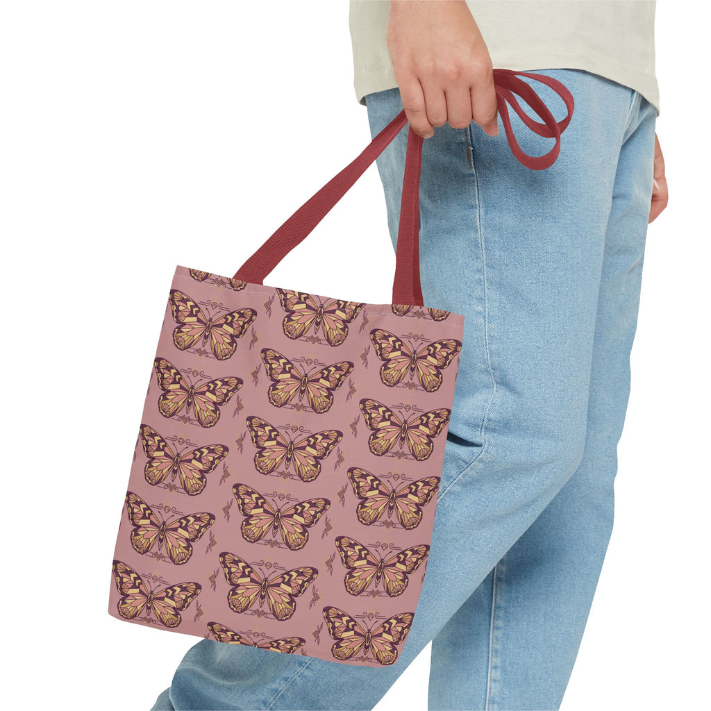 Butterfly-pattern tote bag in pink with brown-red handles, held at the side