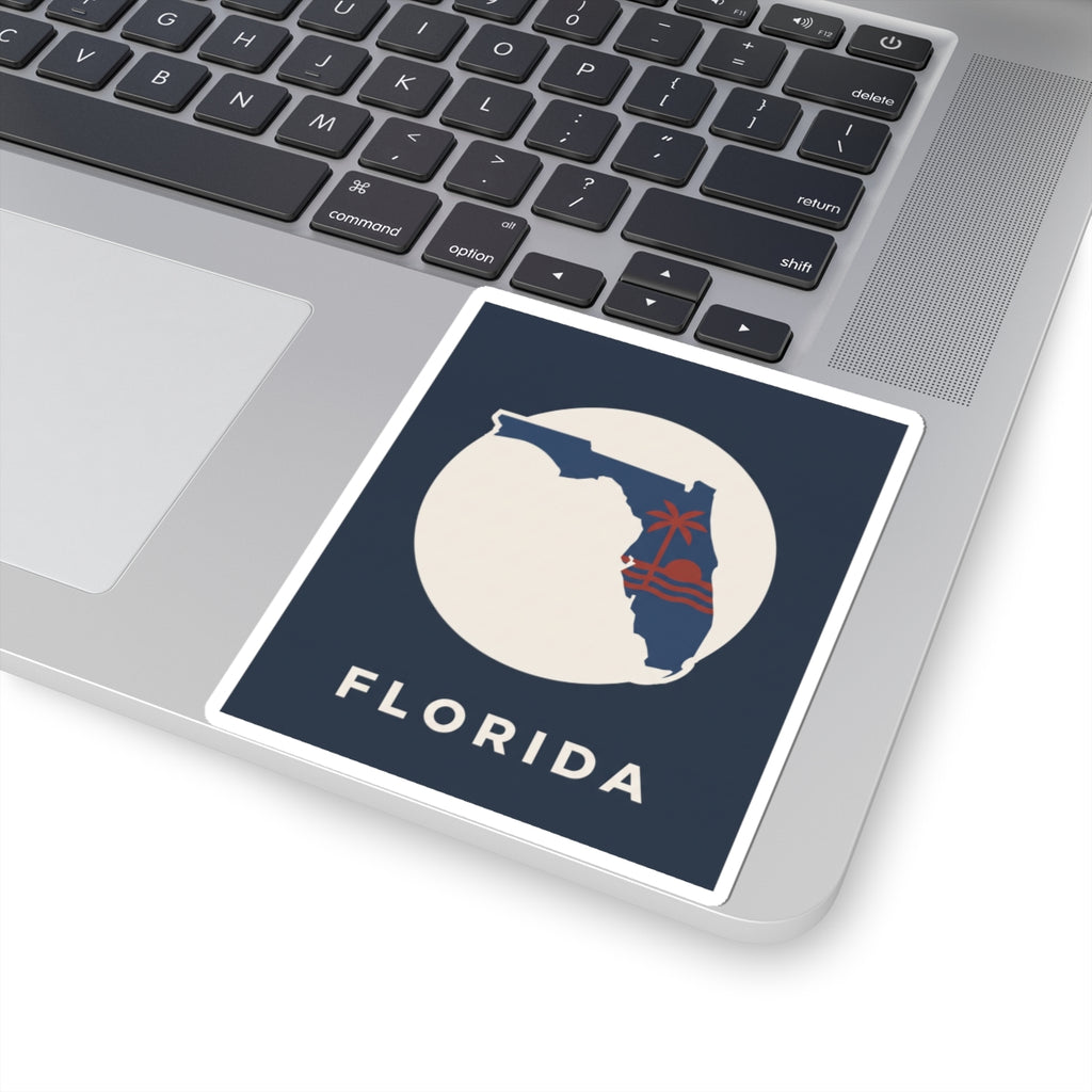 Florida sticker on laptop keyboard: blue square with white circle, red palm tree and FLORIDA
