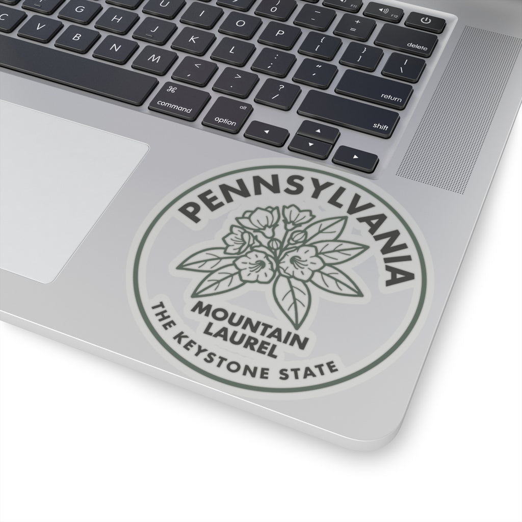 Transparent vinyl sticker on laptop, circular Pennsylvania Mountain Laurel emblem close-up