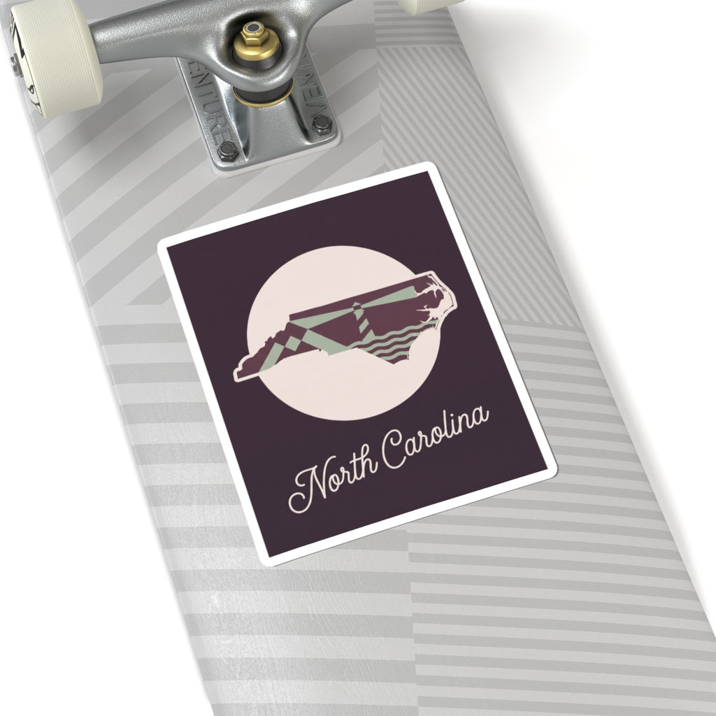 North Carolina kiss-cut decal sticker on roller surface, purple panel with state silhouette